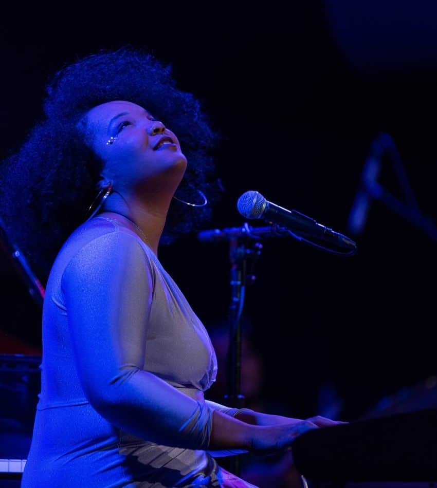 Alexis Lombre playing piano onstage under blue lights