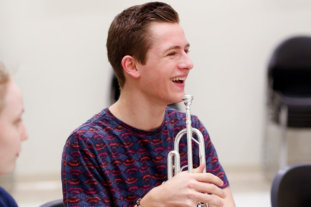 A trumpet player is all smiles during an ensemble class