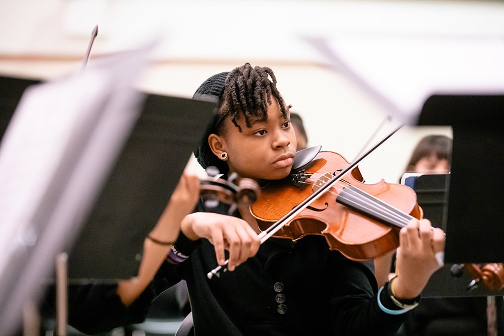 A strings student practicing during a conservatory rehearsal