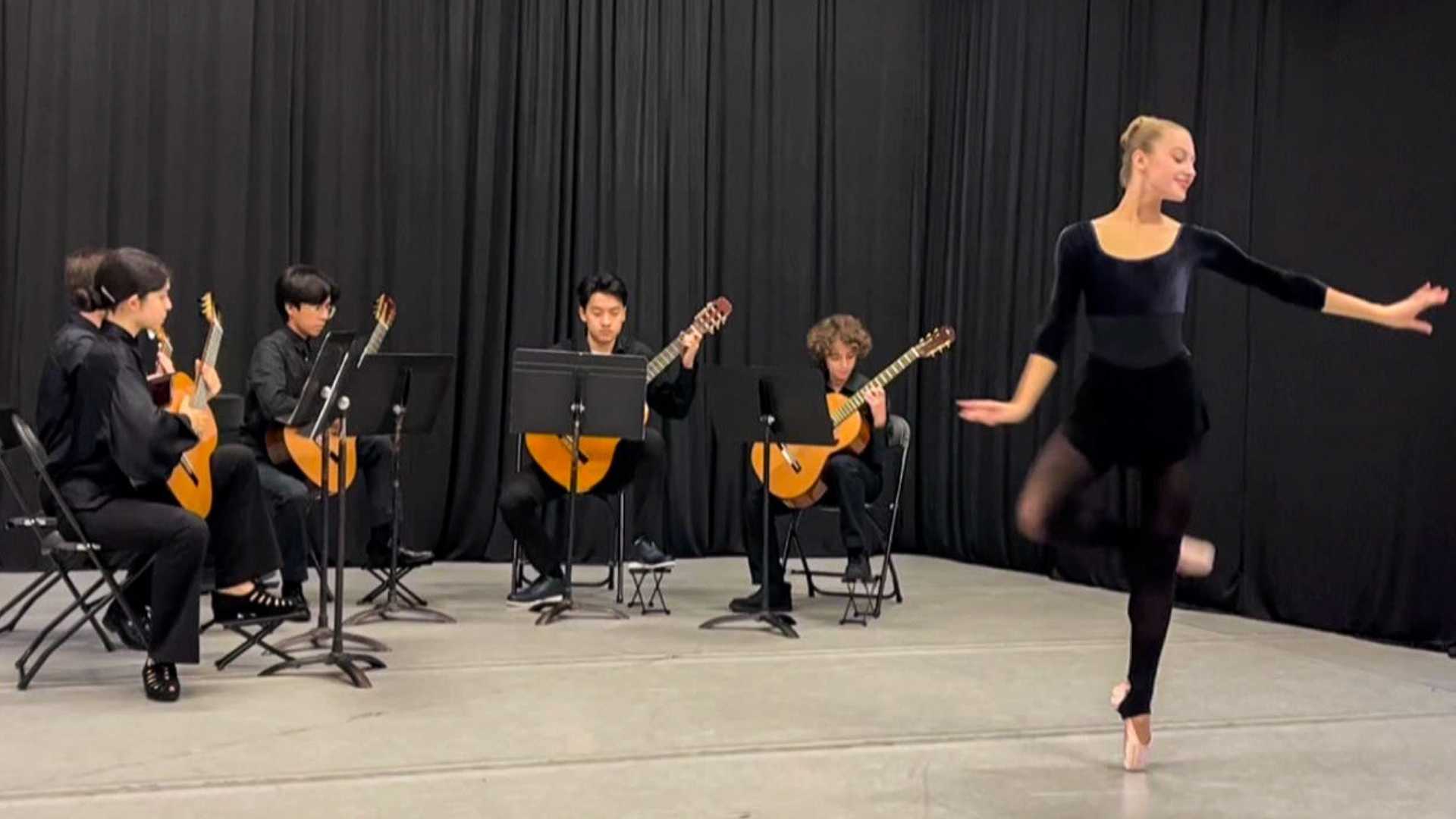 A dancer performs in front of four guitarists