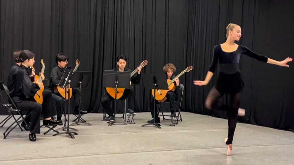 A dancer performs in front of four guitarists