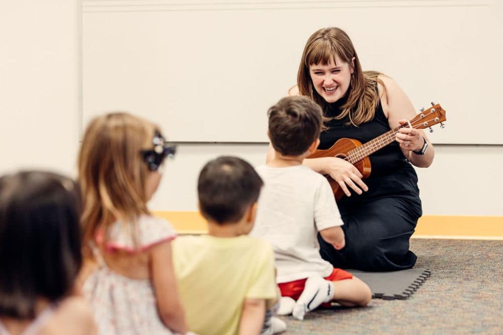 An early childhood group class practicing ukulele with their teacher