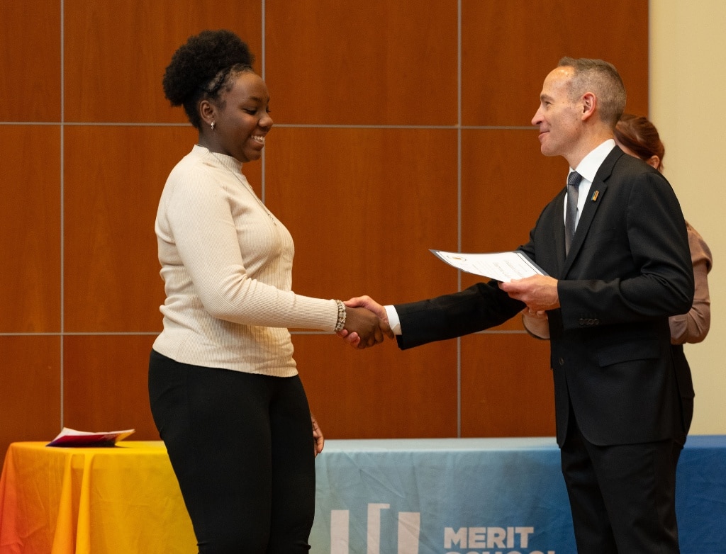 Emaryona Codjoe being handed her diploma by Charlie Grode and shaking his hand.