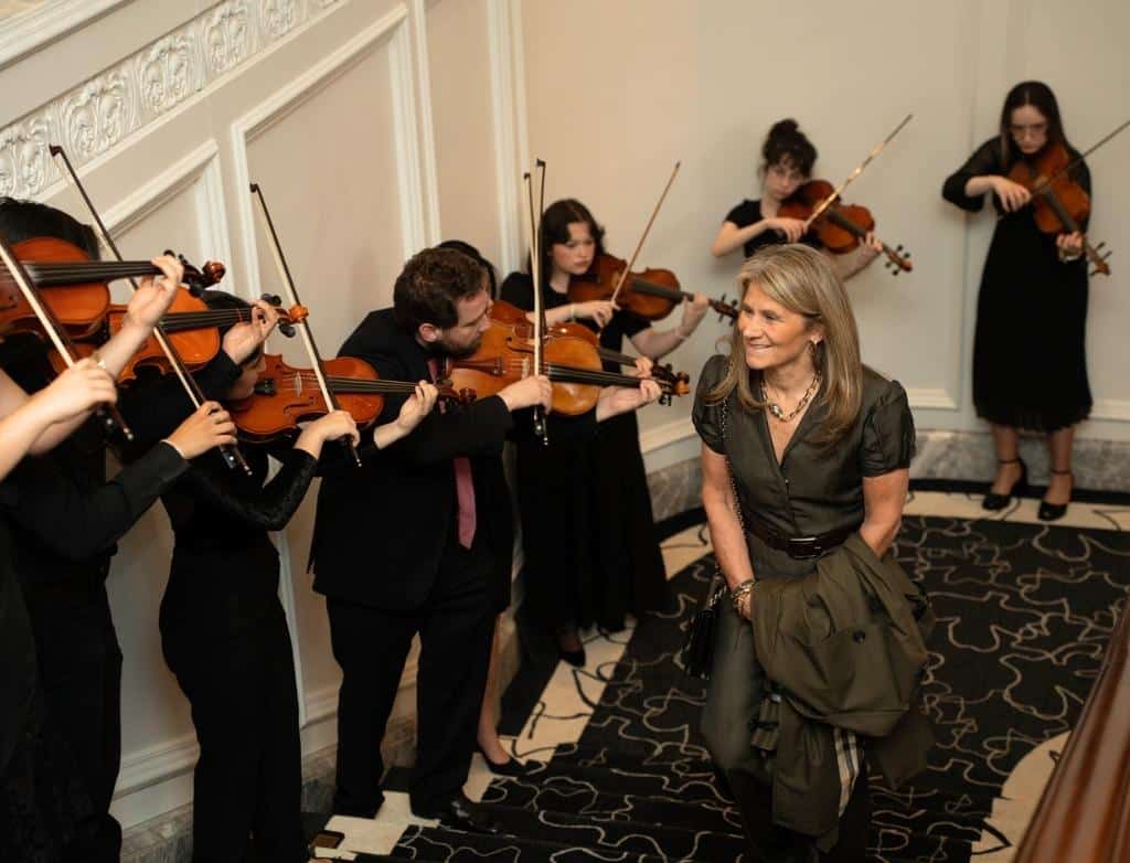 Violinists serenade a guest coming up the stairs