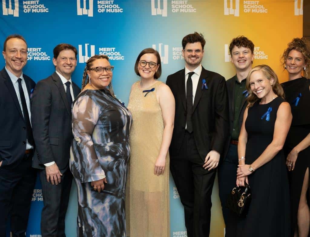 Merit's Associate Board gathers in front of a colorful backdrop