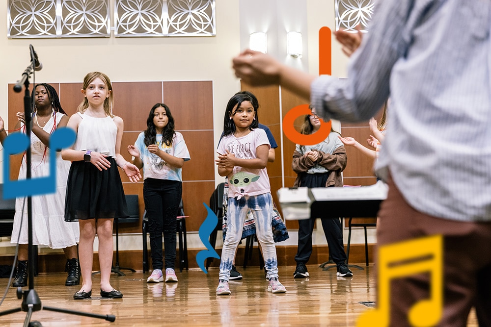 A choir ensemble clapping their hands as they rehearse