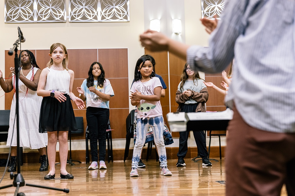 A choir ensemble clapping their hands as they rehearse