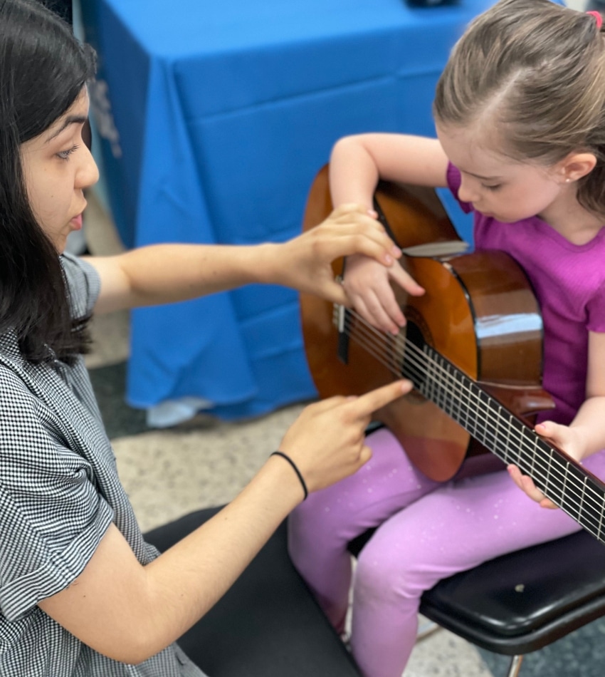 Merit students help younger kids discover musical instruments