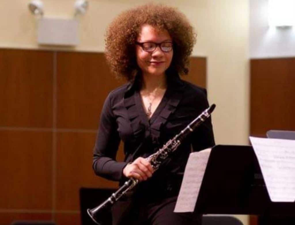 High school Kamila on stage in Gottlieb Hall holding a clarinet.