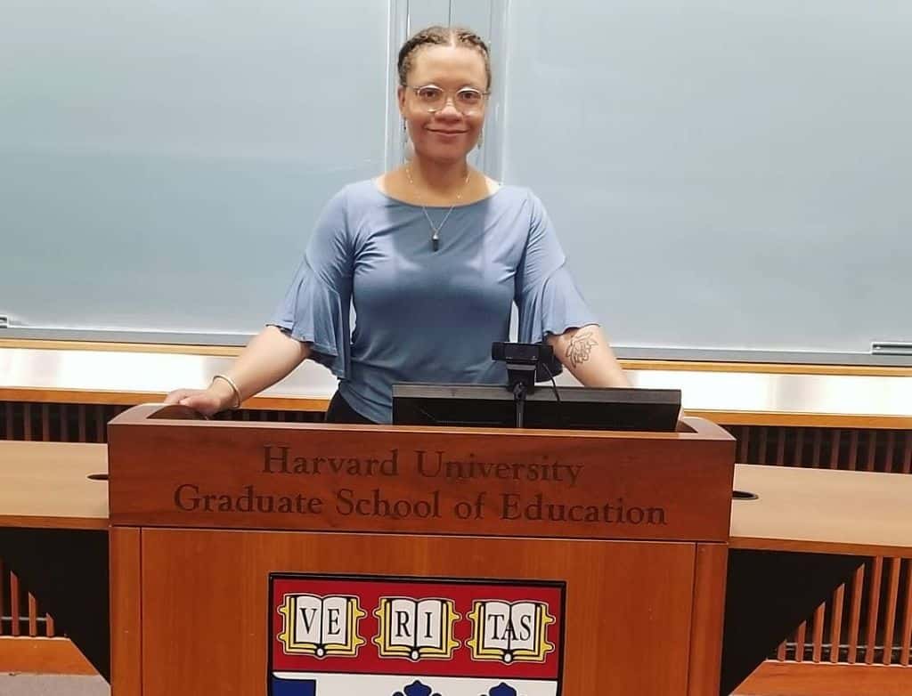 Kamila standing at a podium with the engraving, "Harvard University Graduate School of Education."