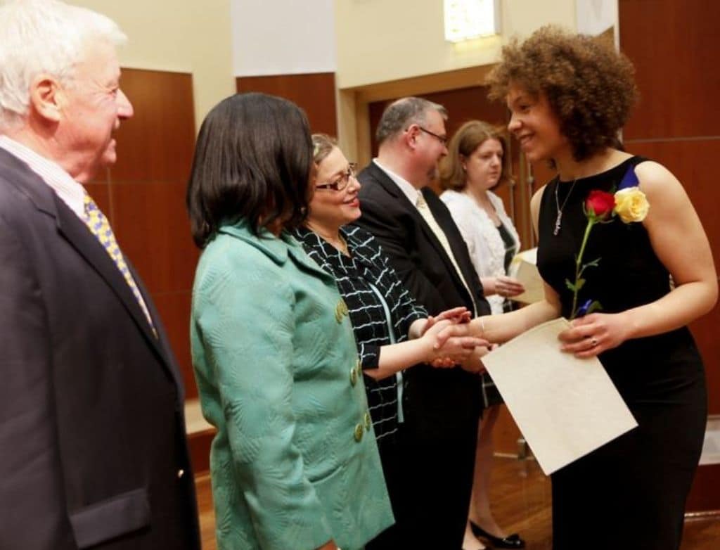 Kamila at Merit's 2012 Graduation shaking Duffie Adelson's hand.