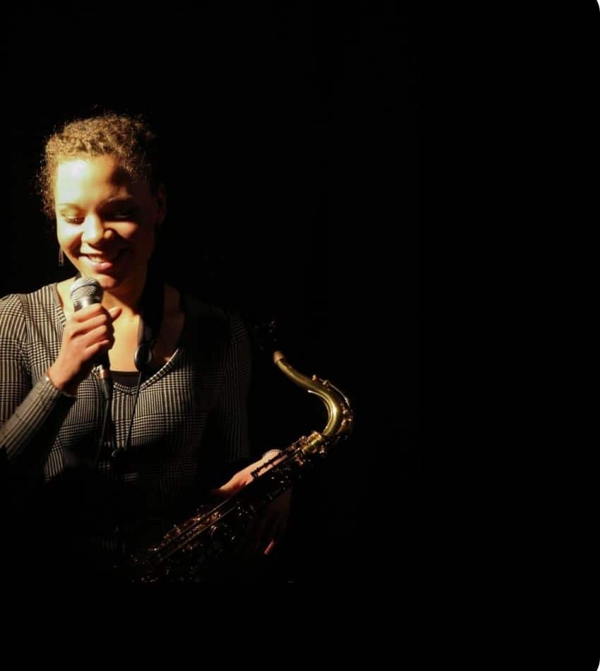 Kamila on stage holder a microphone and a saxaphone.