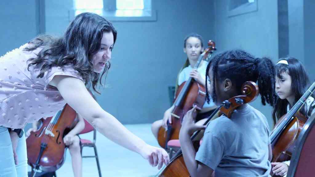 A teacher helps a young cellist