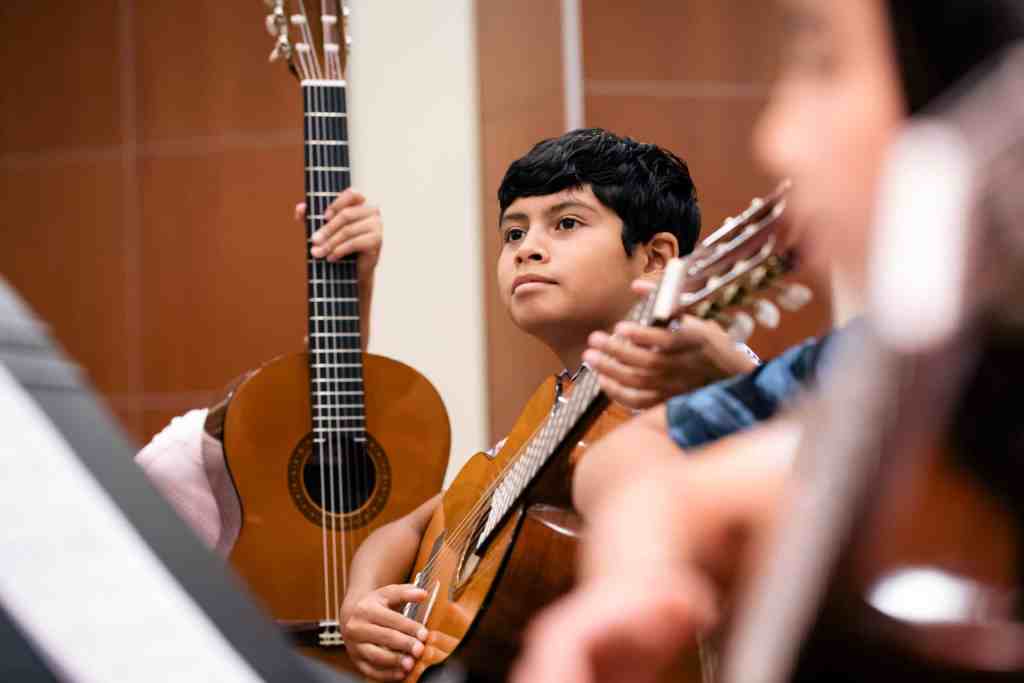 Student listening to instruction during a group guitar class