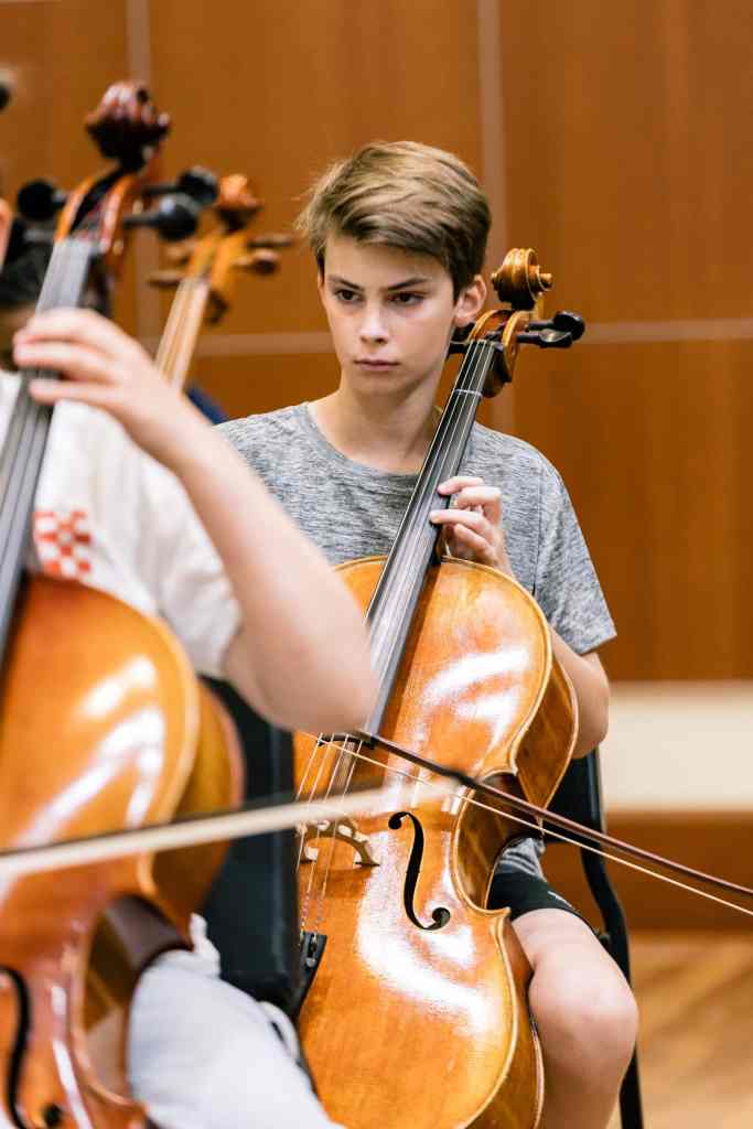 A student playing the cello during a rehearsal