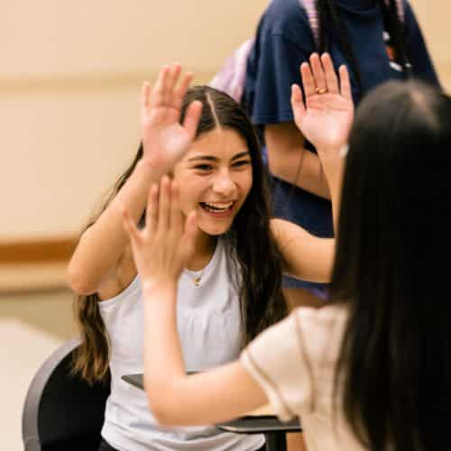 Two music camp students laugh and play a clapping game