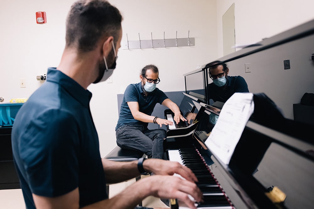 A piano instructor giving direction to his student during a private lesson