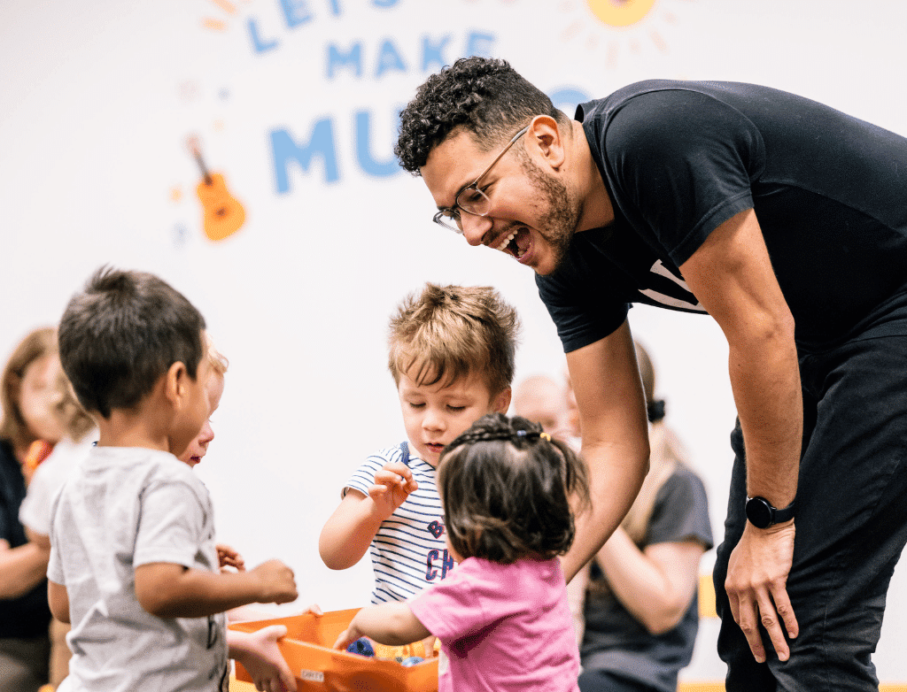 Early Childhood faculty Miro Hernandez with three toddlers gathered in a circle.