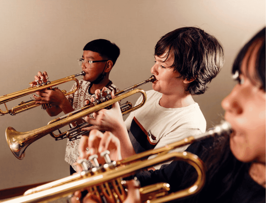 A group of students play trumpets while standing in a line