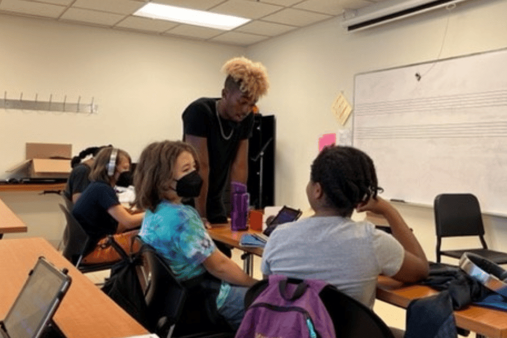 Bryce Thompson helps out students at a desk in a songwriting class.