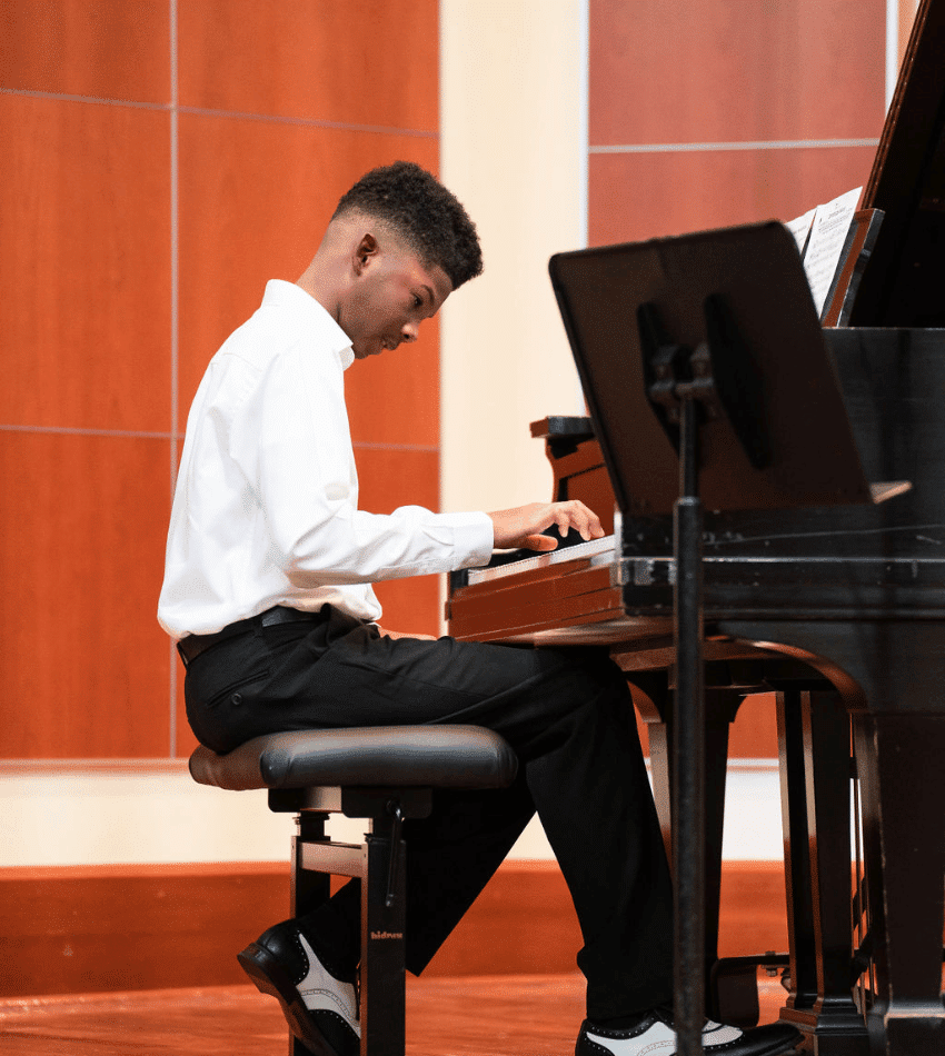 A student plays piano onstage.