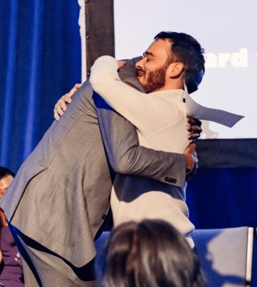 Julian Reid and Nico Segal hug onstage at Merit's Gala 2023.