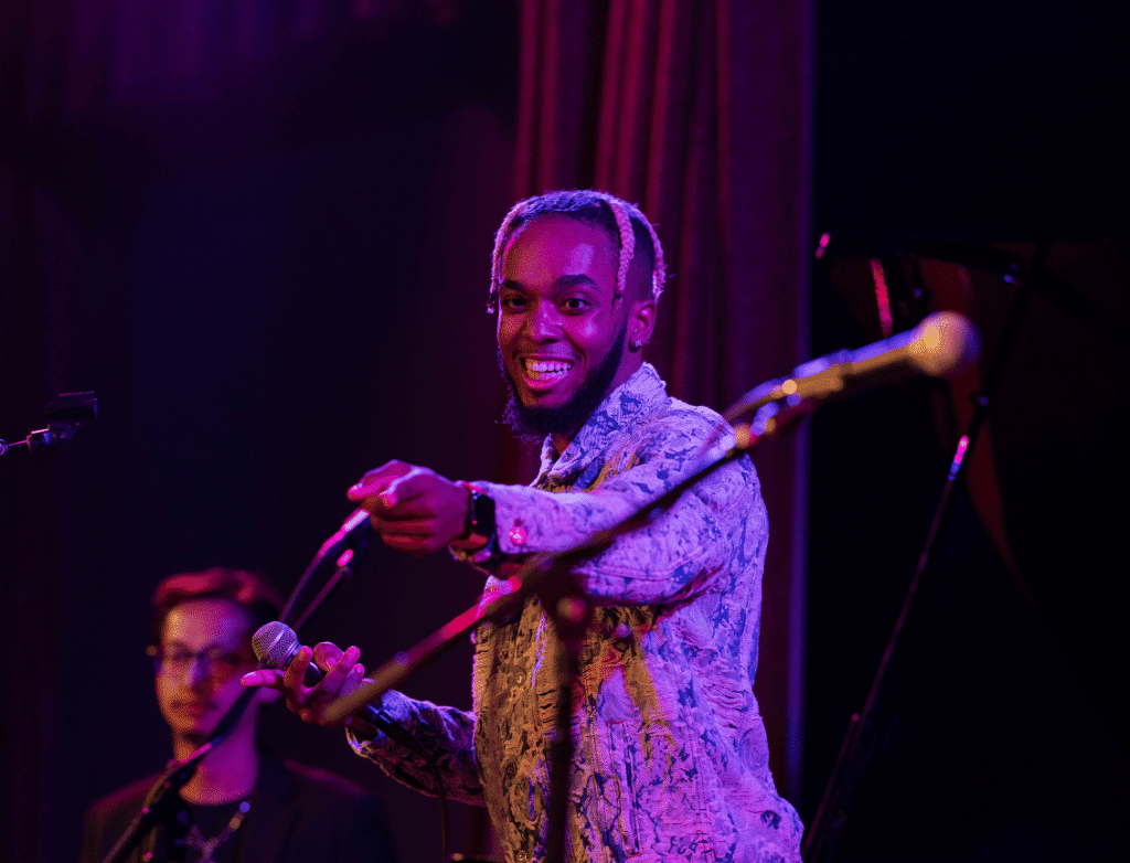 King Melik smiles, pointing at the audience during a performance.