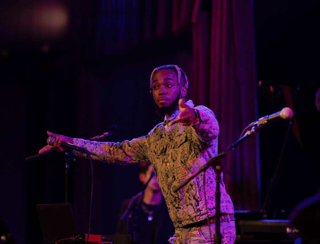 King Melik on stage, holding out his hands to the audience.