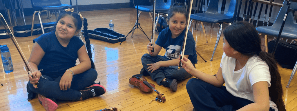 young strings players showing off their bows for their string instruments