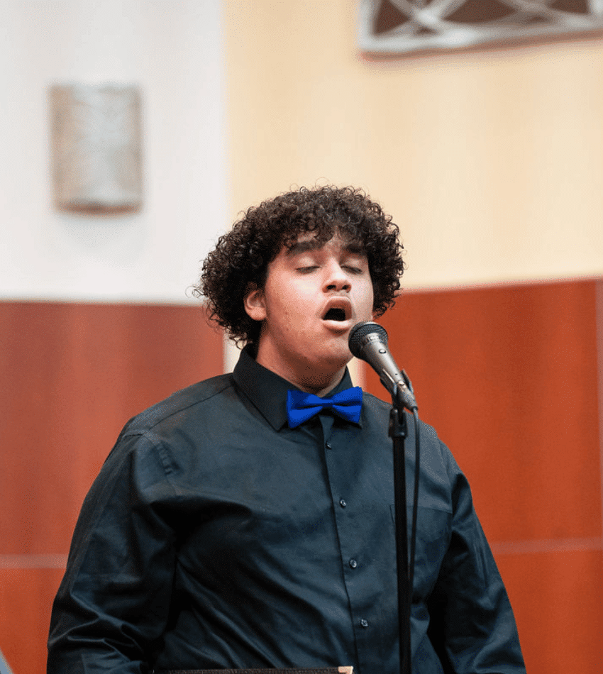 A singer stands onstage singing at a microphone.